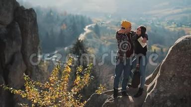 恋爱中的年轻夫妇站在岩石上，拍了一张自拍肖像。 拜访著名游客的男人和女人